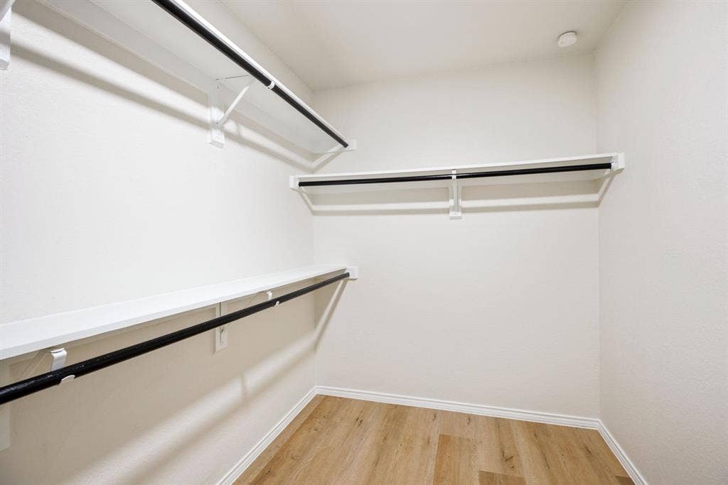 Neutral wall paint, wood-finish flooring, and built-in shelving with hanging rods