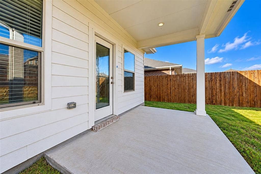 Covered concrete patio with white siding, recessed lighting, and a glass-paneled exterior door