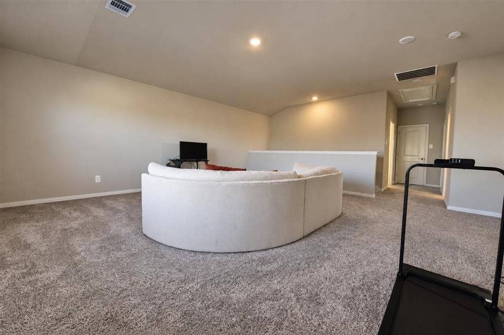 Carpeted upper level with vaulted ceiling, recessed lighting, and a partial wall separation