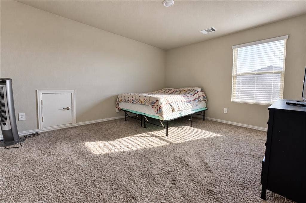 Wall-to-wall carpeting and a single window with horizontal blinds
