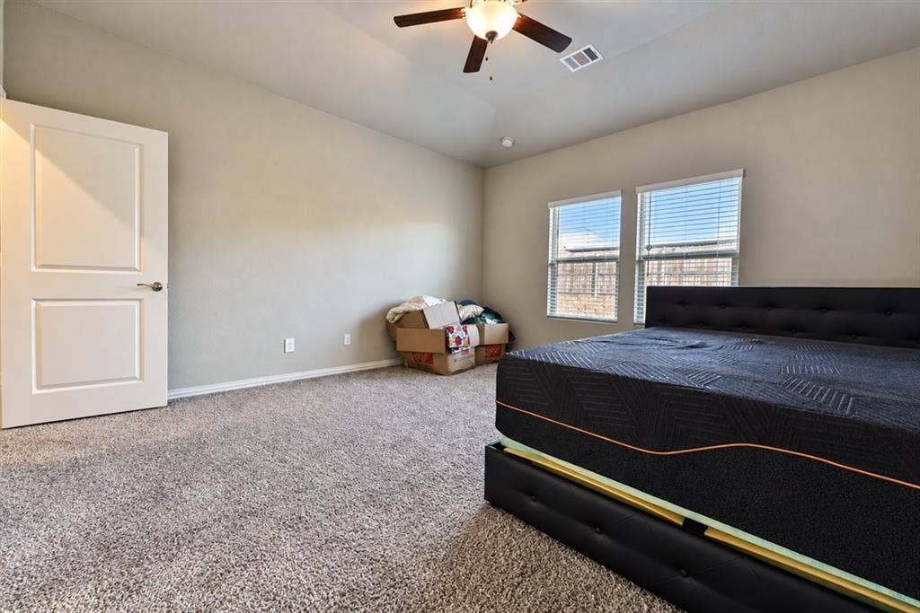 Neutral wall tones with carpeted flooring, a ceiling fan with integrated lighting, and two windows with blinds