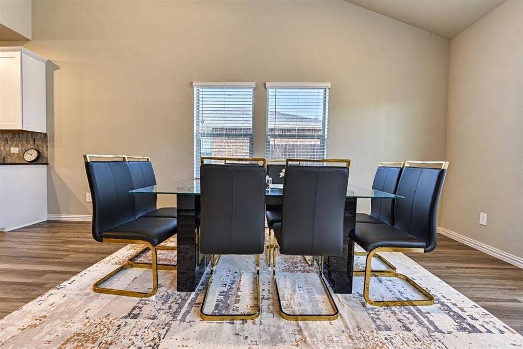 Vaulted ceilings, wood-finish flooring, white cabinetry, tiled backsplash, and natural light