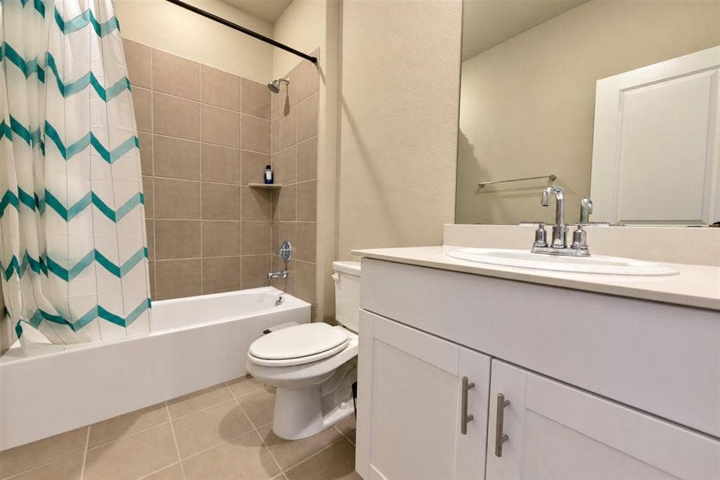 White vanity with shaker-style cabinetry, a built-in sink, and a light-toned countertop