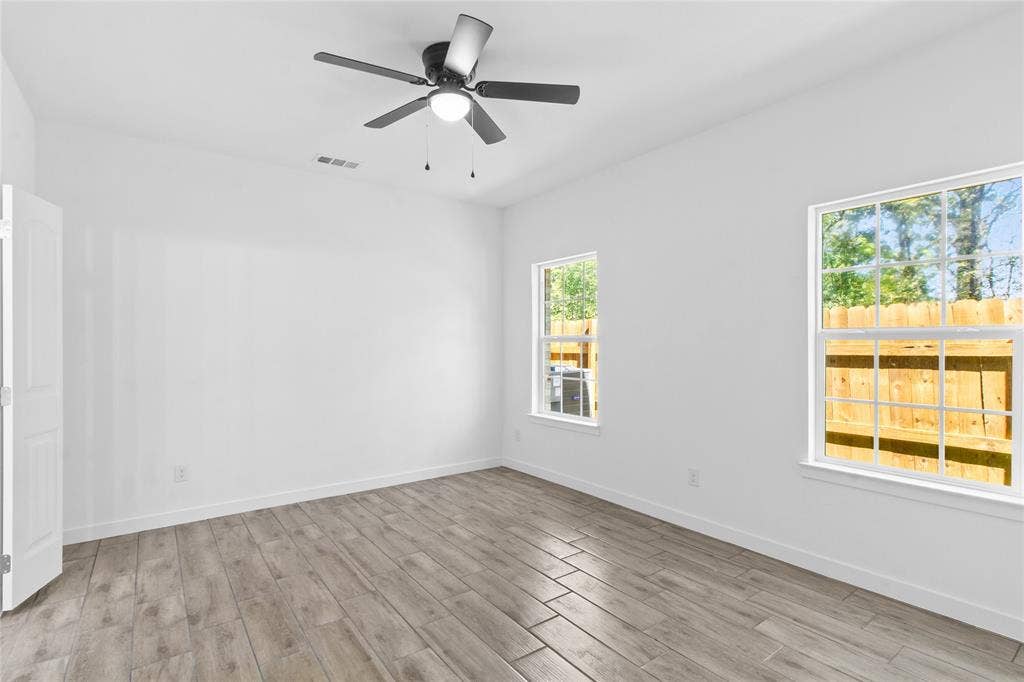 7520 Double Bridge Road, Mabank, TX 75156 White walls, wood-finish flooring, two window openings, and a ceiling fan with integrated lighting