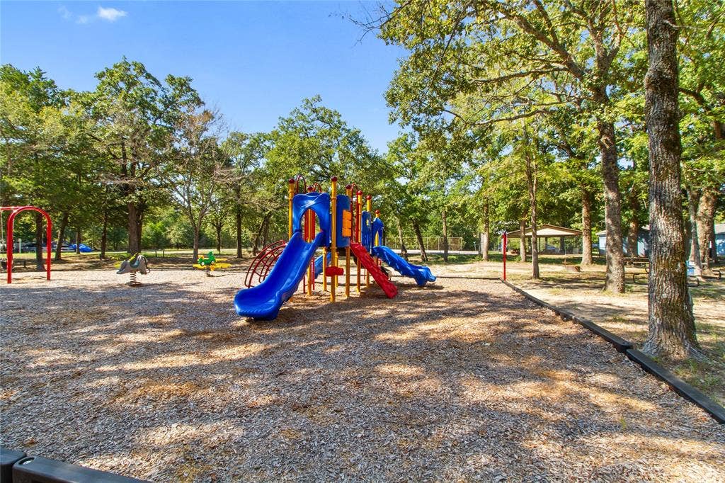 7520 Double Bridge Road, Mabank, TX 75156 Playground area featuring a multi-slide play structure, swing set, and spring riders set on a wood chip surface