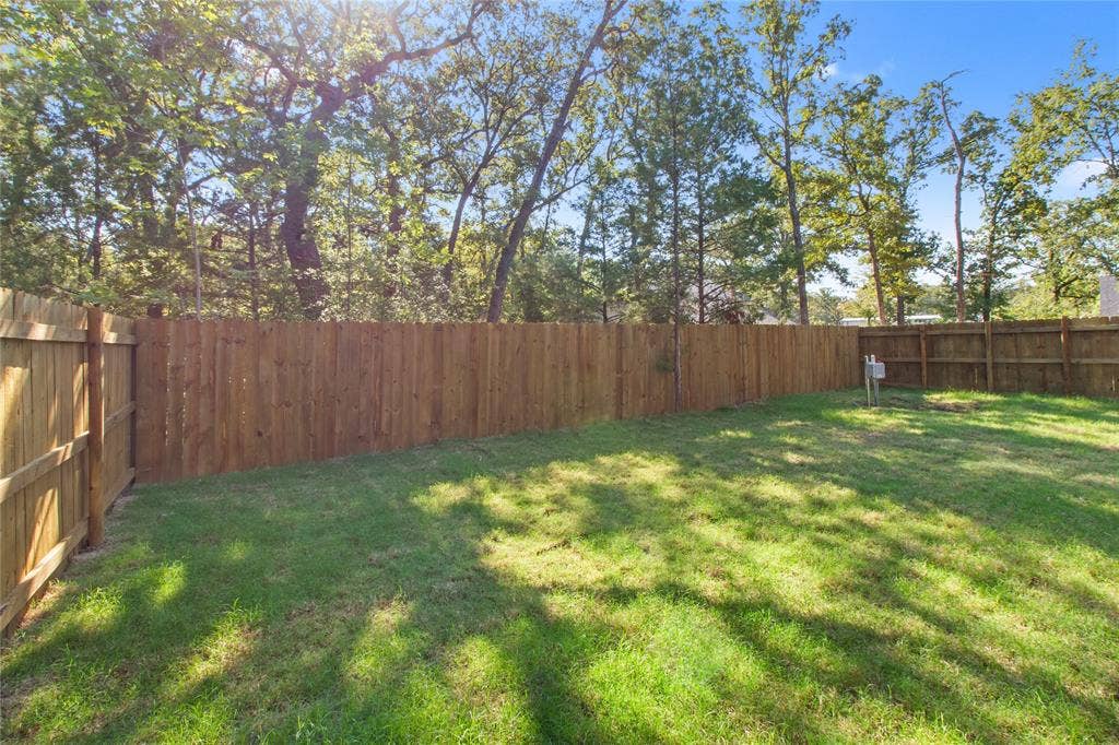 7520 Double Bridge Road, Mabank, TX 75156 Expansive lawn area with a perimeter wood privacy fence, surrounded by mature trees