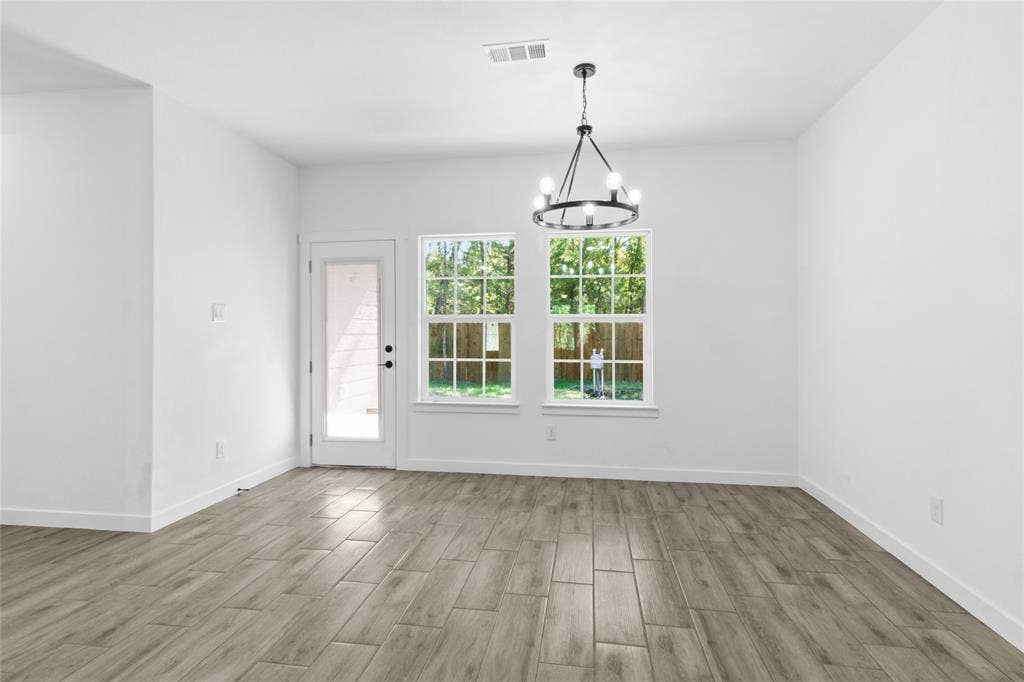 7520 Double Bridge Road, Mabank, TX 75156 Wood-finish plank flooring, white walls, black chandelier, double-pane windows, and a glass-paneled exterior door