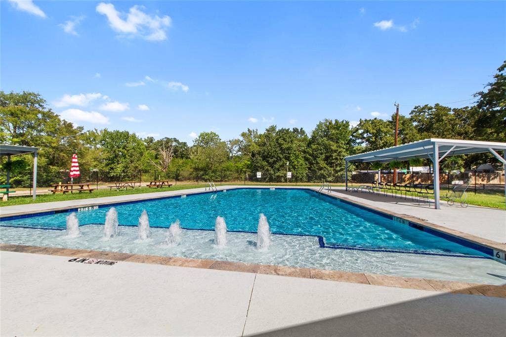7520 Double Bridge Road, Mabank, TX 75156 Resort-style swimming pool featuring crystal-clear water, multiple water fountains, concrete decking, and overhead shade structures