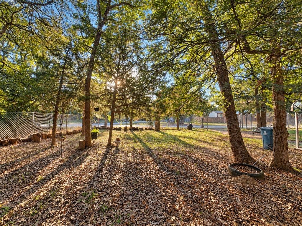 632 Cumberland Trail, Valley View, TX 76272 Expansive yard featuring mature trees, natural ground cover, and secure chain-link fencing
