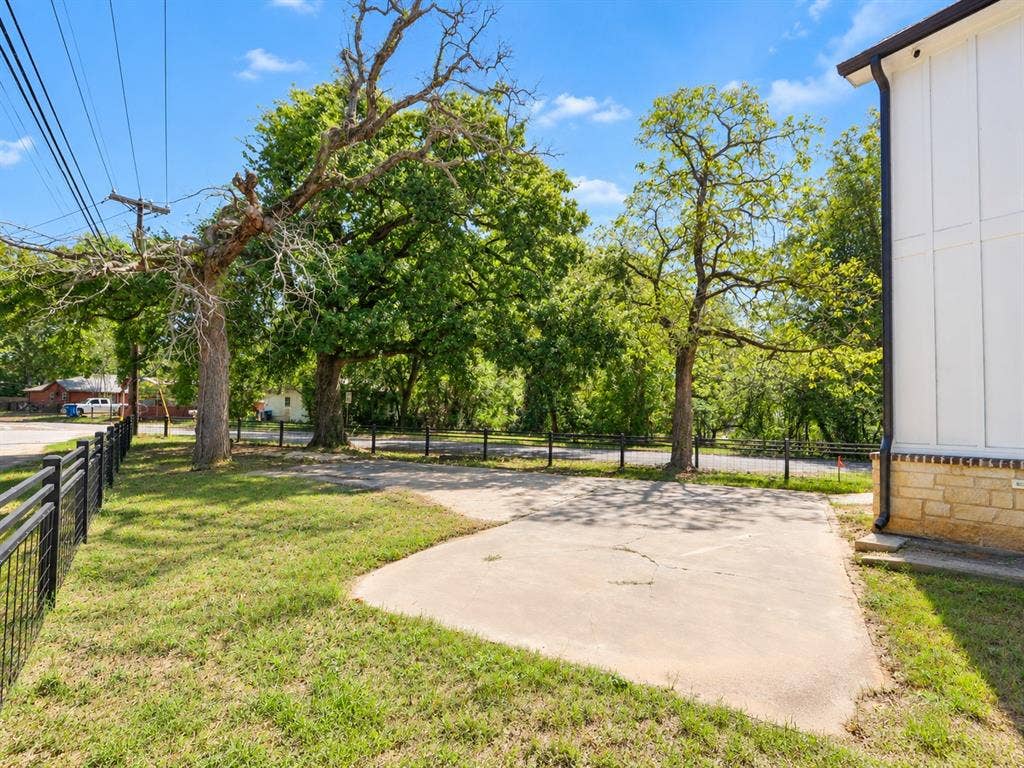 521 York Street, Athens, TX 75751 Concrete pad with surrounding grass, mature trees, and a black metal fence