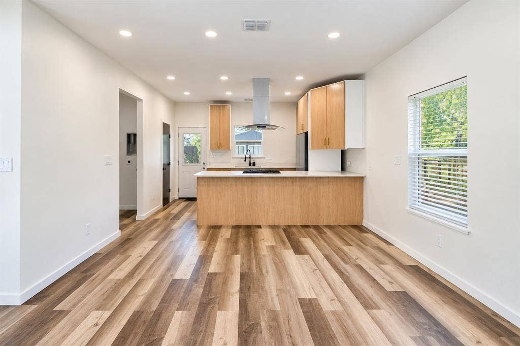 521 York Street, Athens, TX 75751 Wood-finish flooring, recessed lighting, two-tone cabinetry, stainless steel appliances, and a kitchen island with a light-colored countertop