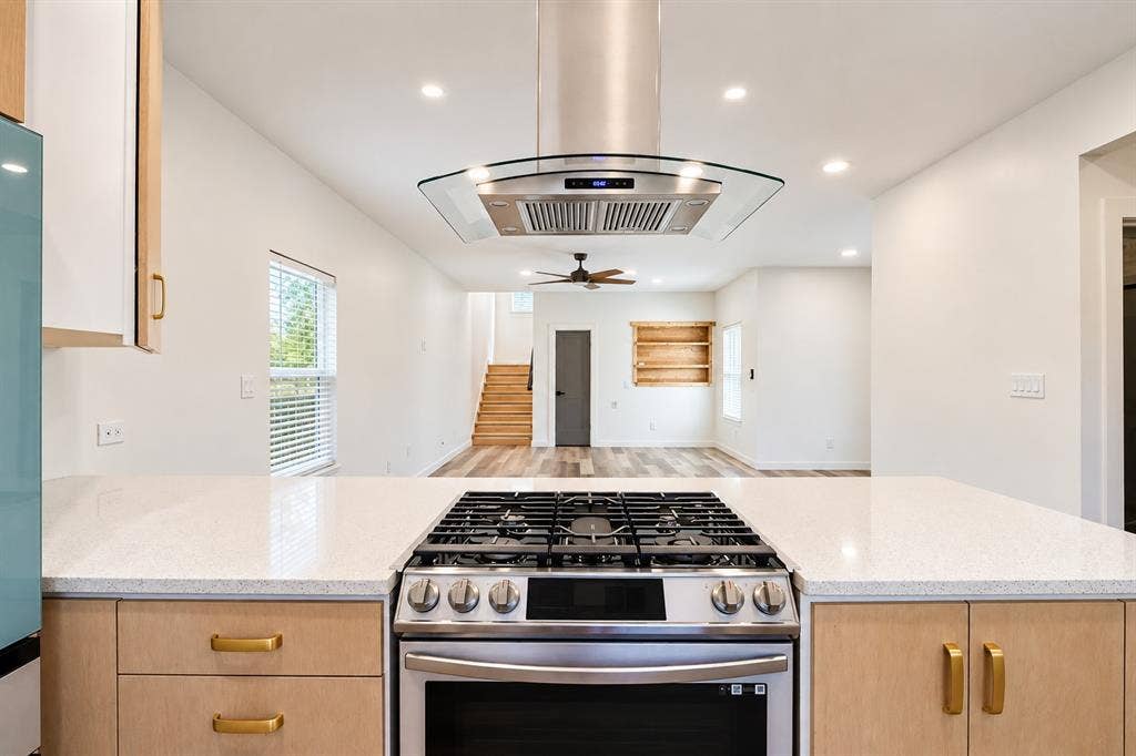 521 York Street, Athens, TX 75751 Stainless steel range with a glass-canopy range hood, white quartz countertops, light wood-finish cabinetry, and recessed lighting