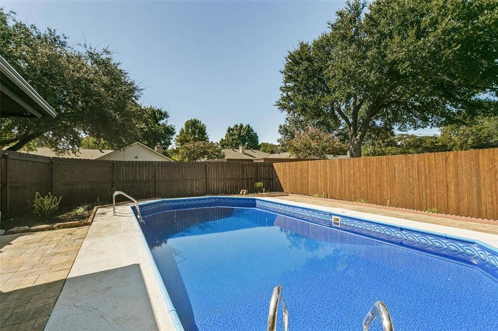 2704 Parkhaven Drive, Plano, TX 75075 In-ground swimming pool with a patterned liner, concrete deck, and perimeter wood fencing