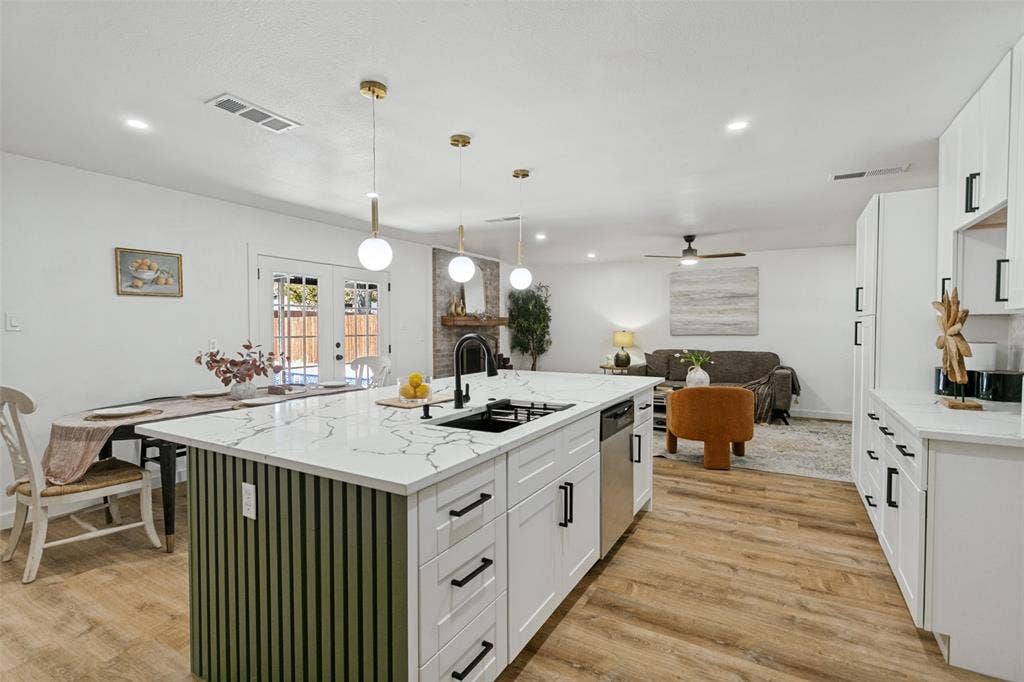 2704 Parkhaven Drive, Plano, TX 75075 Kitchen island featuring a white quartz-finish countertop, integrated sink with matte black fixture, and green slatted base