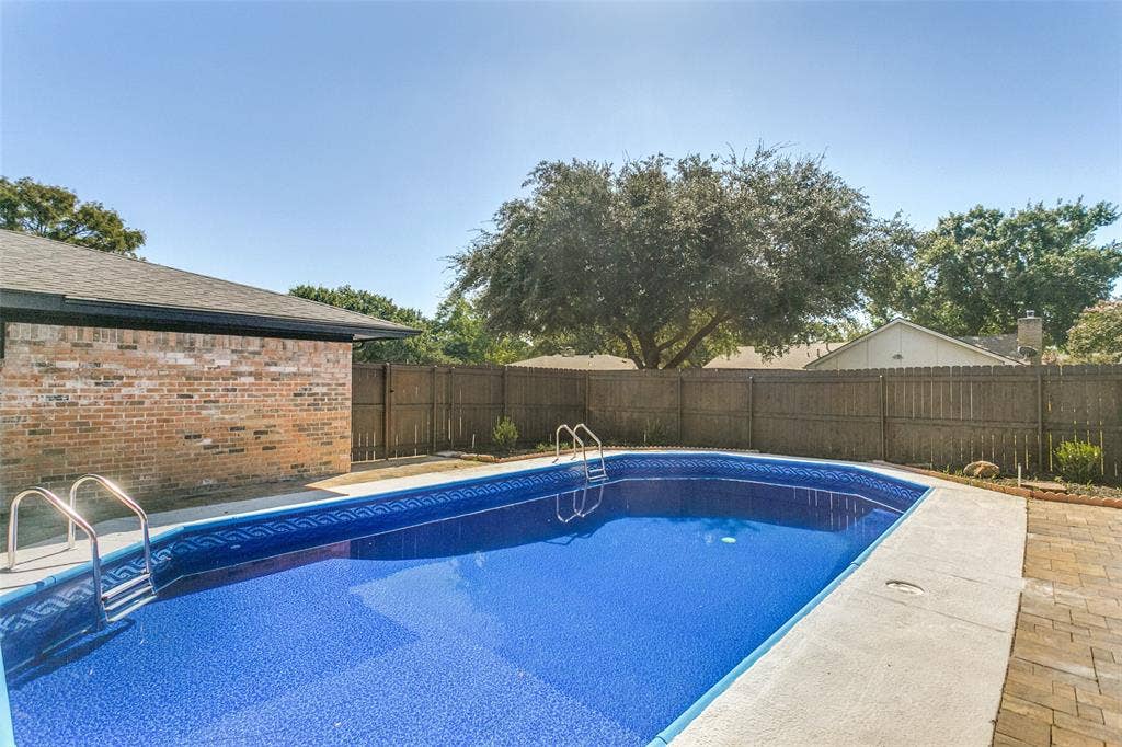 2704 Parkhaven Drive, Plano, TX 75075 In-ground swimming pool with a blue patterned liner, surrounded by concrete coping and paver hardscaping