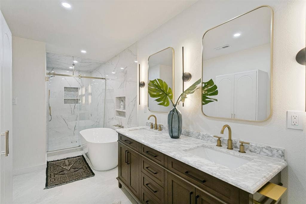 2704 Parkhaven Drive, Plano, TX 75075 Dual vanity with stone countertop, freestanding soaking tub, glass-enclosed shower, and built-in wall niches