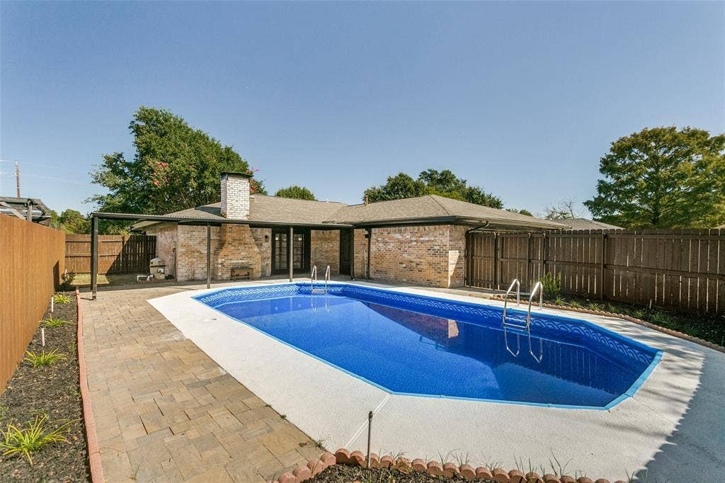2704 Parkhaven Drive, Plano, TX 75075 Backyard featuring a built-in swimming pool with a concrete surround, paver patio, full privacy fencing, and brick exterior