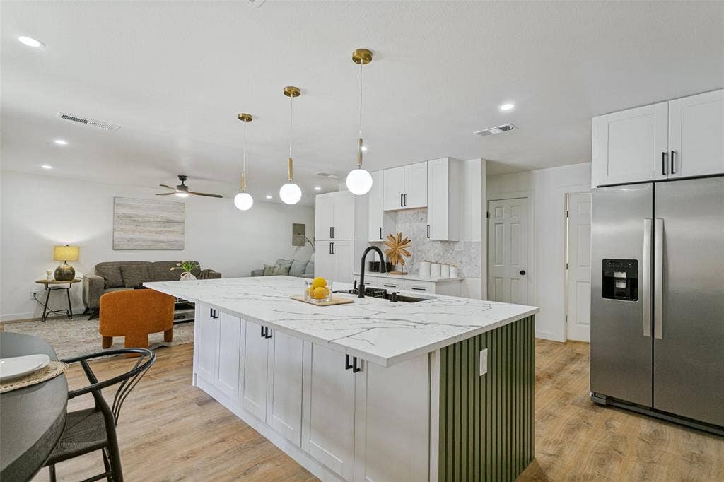 2704 Parkhaven Drive, Plano, TX 75075 Kitchen island featuring a white countertop with dark veining, integrated sink, and matte black faucet