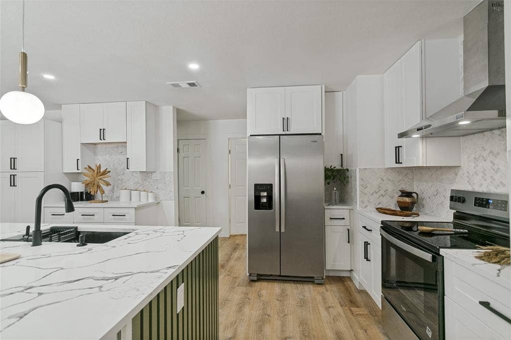 2704 Parkhaven Drive, Plano, TX 75075 Modern kitchen featuring white cabinetry, stainless steel appliances, marble-look countertops, and wood-finish flooring