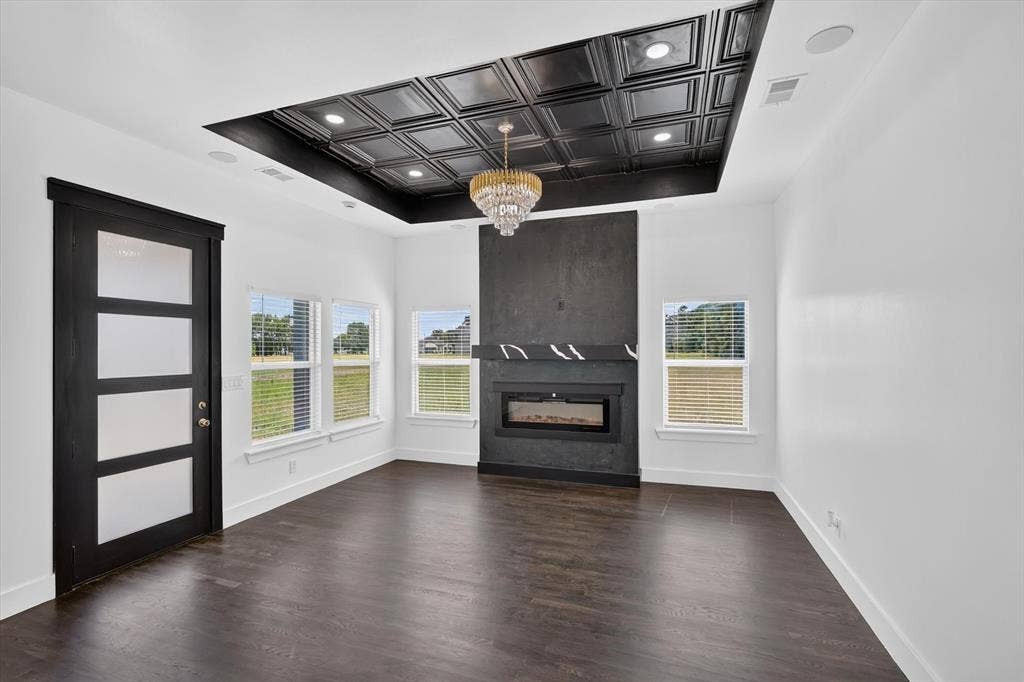 102 Shadywood Road, Trinidad, TX 75163 Recessed ceiling with decorative black tile inlay, central chandelier, dark wood-finish flooring, and a built-in fireplace with a stone mantel