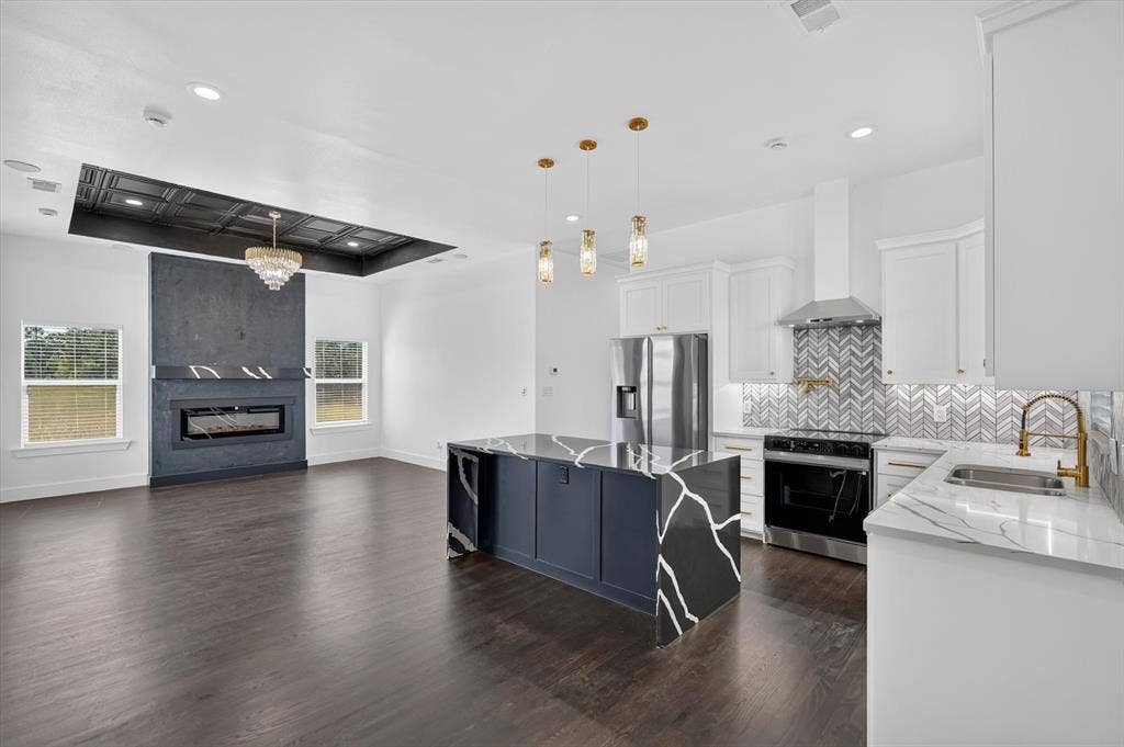 102 Shadywood Road, Trinidad, TX 75163 Open-concept living space featuring wood-finish flooring, a contemporary fireplace, and a kitchen island with a waterfall countertop