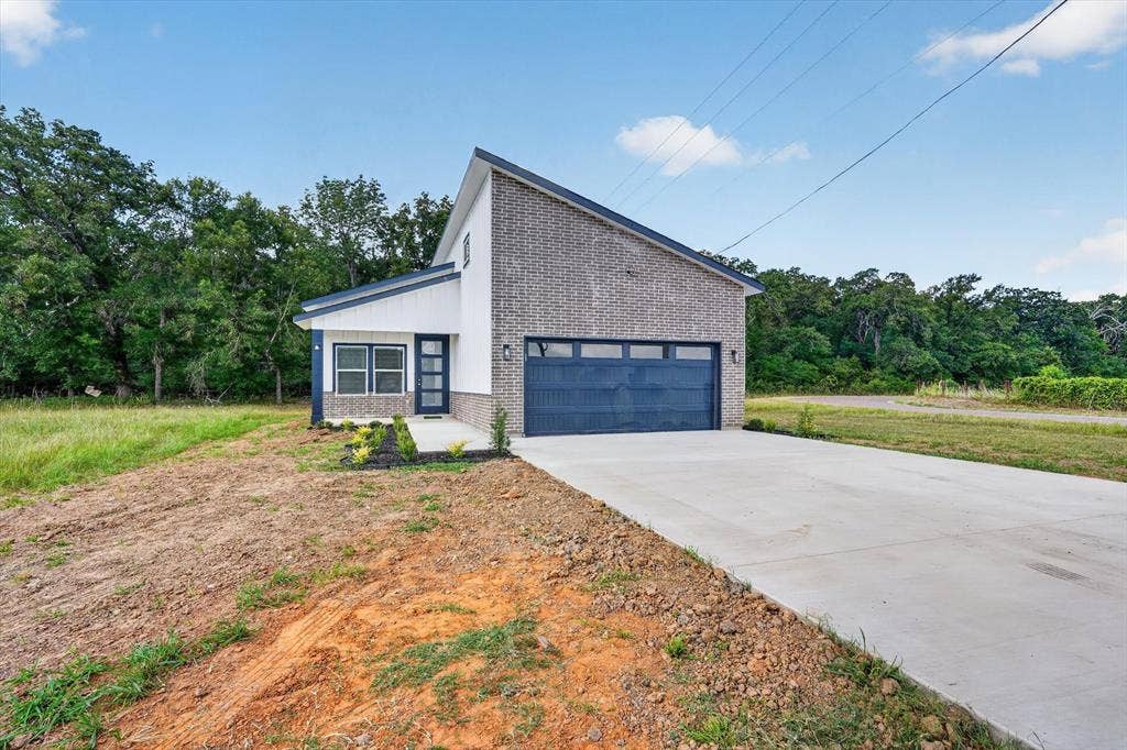 102 Shadywood Road, Trinidad, TX 75163 Contemporary exterior featuring brick and horizontal siding, an attached two-car garage, a concrete driveway, and a covered entry