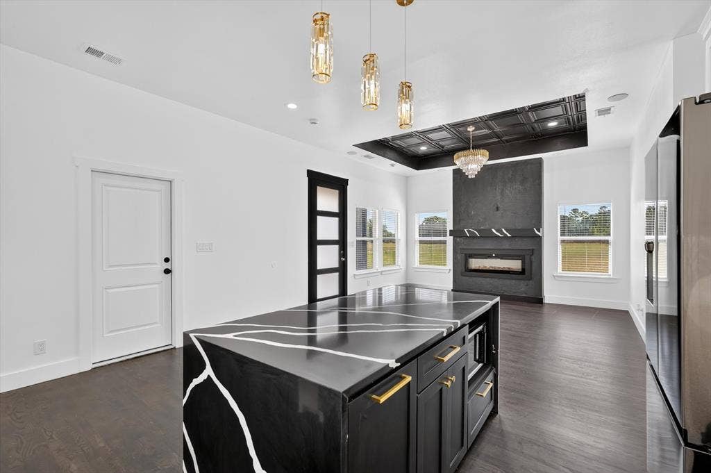 102 Shadywood Road, Trinidad, TX 75163 Spacious open-concept interior featuring wood-finish flooring, a custom island with a unique countertop, a fireplace with a textured surround, and recessed ceiling details with integrated lighting