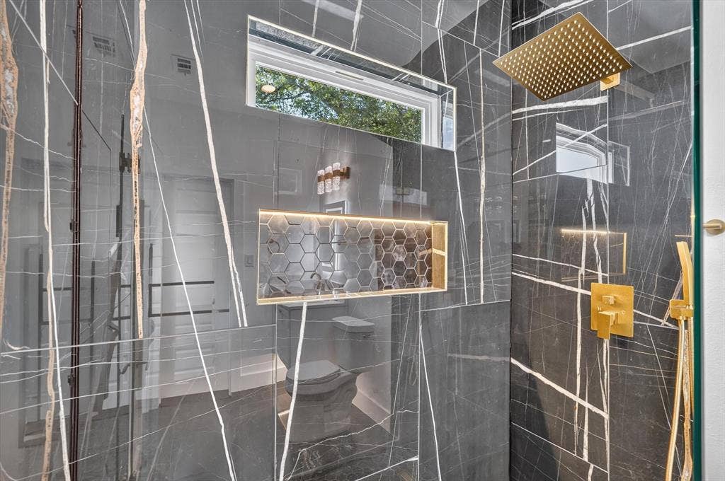 102 Shadywood Road, Trinidad, TX 75163 Shower with large format stone-finish wall tiling, gold-finish fixtures, and a recessed niche with honeycomb tile