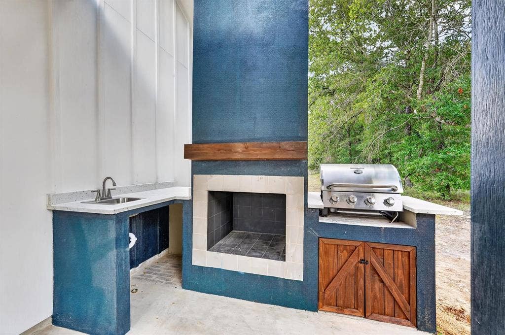 102 Shadywood Road, Trinidad, TX 75163 Outdoor kitchen featuring a built-in grill, integrated sink, and wood-front storage cabinetry