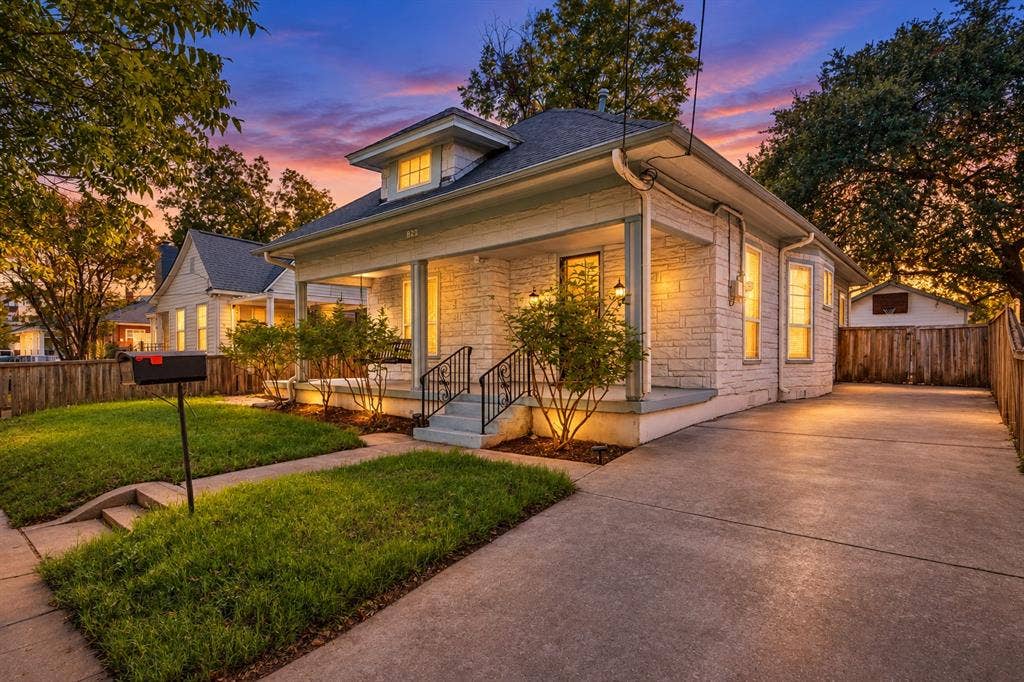 Stone veneer exterior with a covered front porch, concrete driveway, and a dormer window