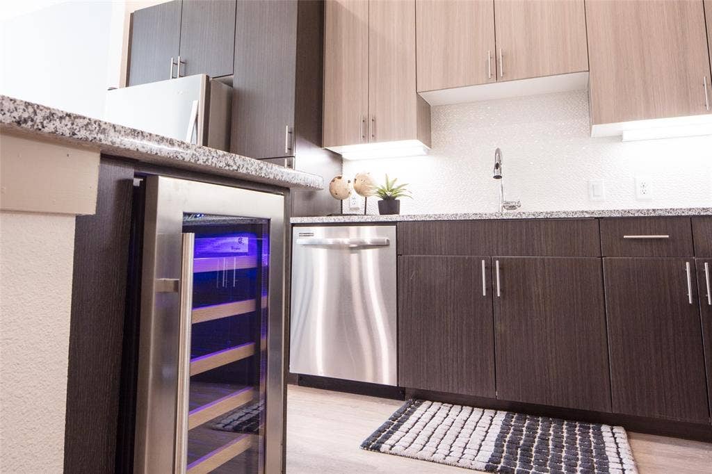 901 N Zang Boulevard, #302, Dallas, TX 75208 Kitchen featuring wine cooler, light stone countertops, light hardwood / wood-style flooring, stainless steel dishwasher, and sink