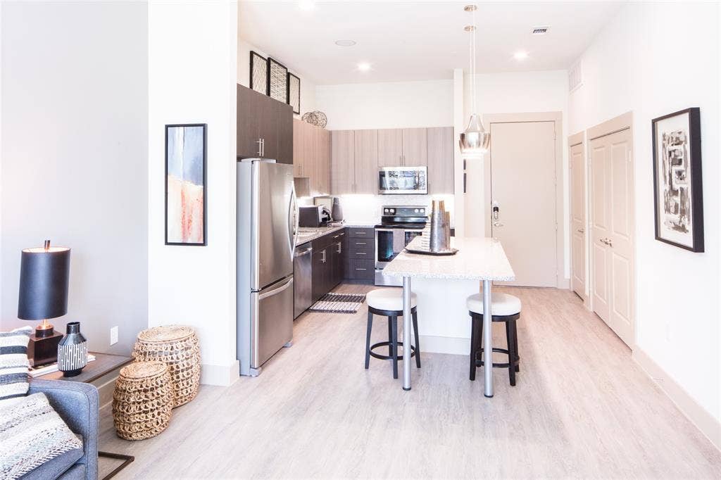 901 N Zang Boulevard, #302, Dallas, TX 75208 Kitchen featuring a breakfast bar, decorative light fixtures, light hardwood / wood-style flooring, appliances with stainless steel finishes, and a center island