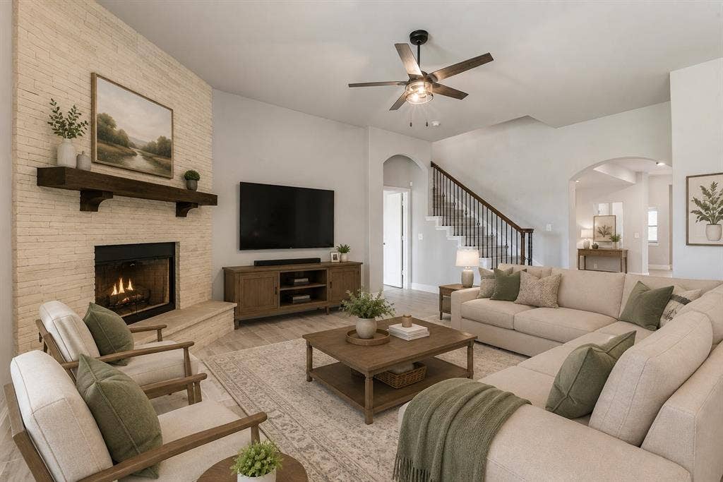 Living area with a stone-clad fireplace, wood-finish flooring, and a ceiling fan