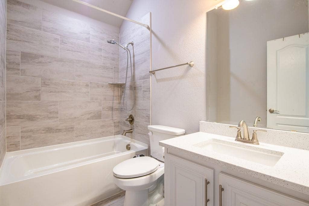 White vanity with brushed nickel hardware, integrated sink, and a speckled countertop