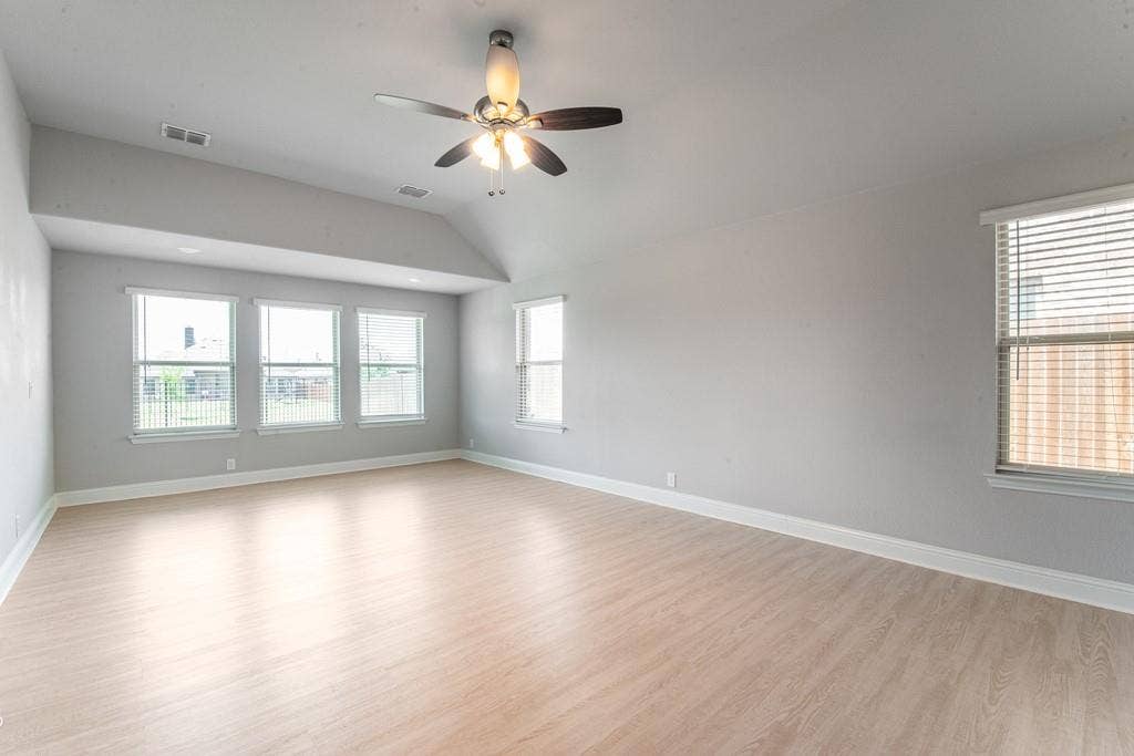Vaulted ceiling with a ceiling fan, recessed lighting, wood-finish flooring, and multiple windows