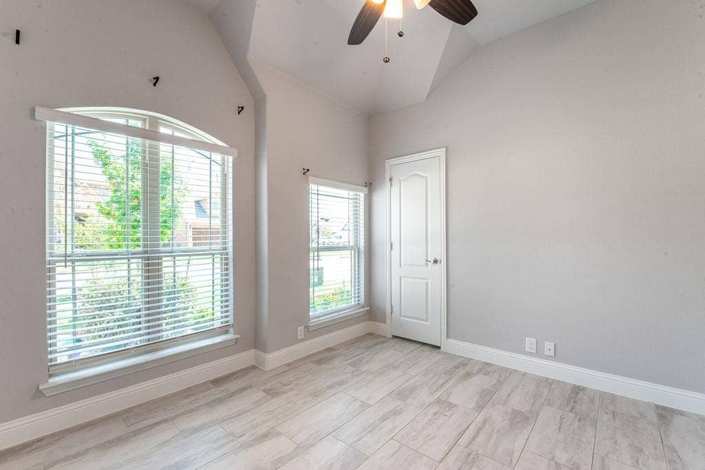Vaulted ceiling with a ceiling fan, wood-finish flooring, and white trim throughout