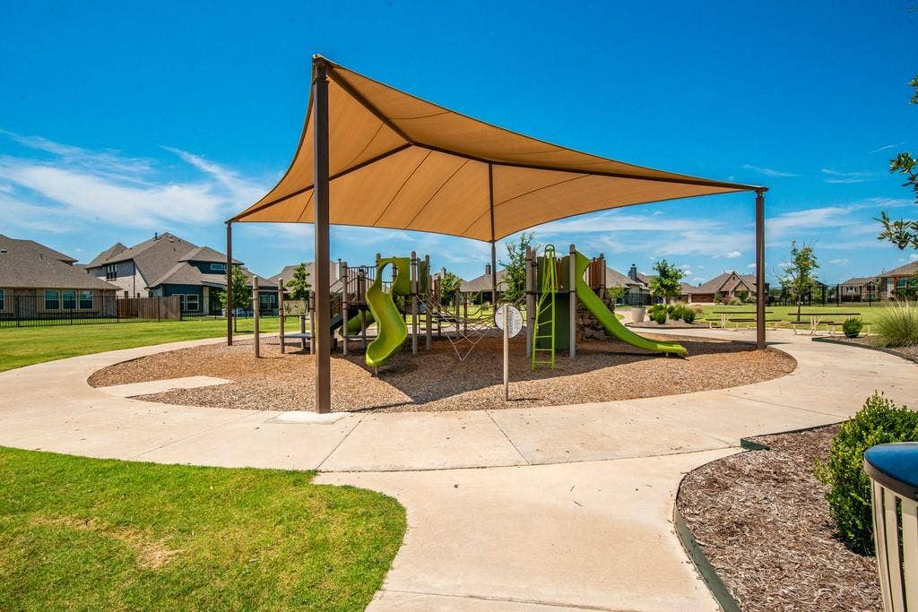 Community playground featuring a shade canopy, multiple slides, and wood chip ground cover
