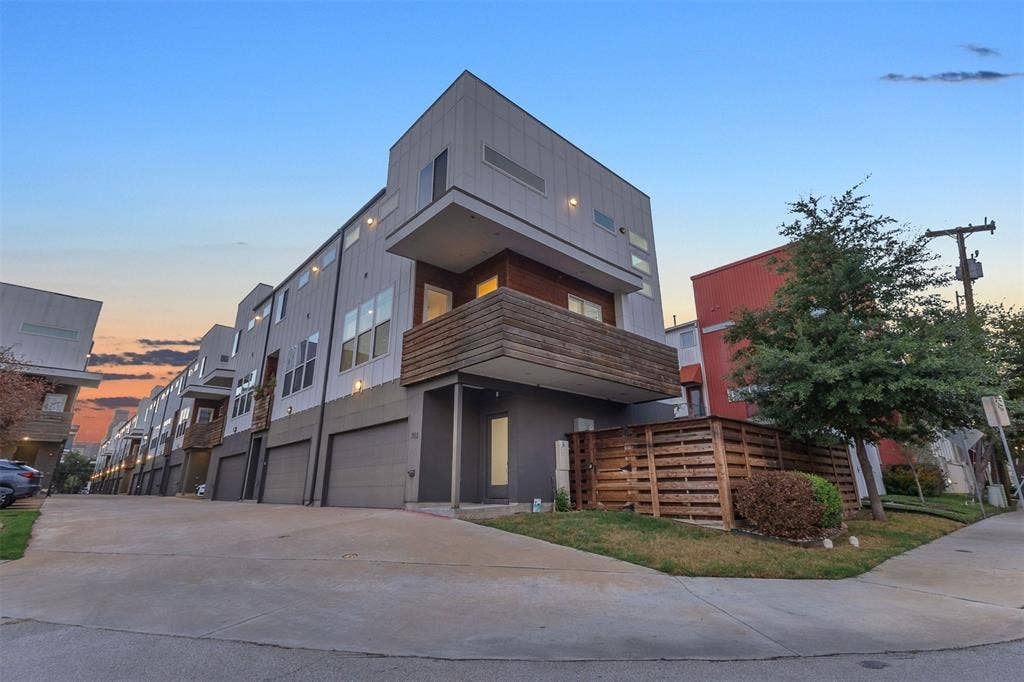 1510 N Washington Avenue, #703, Dallas, TX 75204 Wide view along the shared drive showing the corner condo, its fenced side yard and neighboring units at dusk