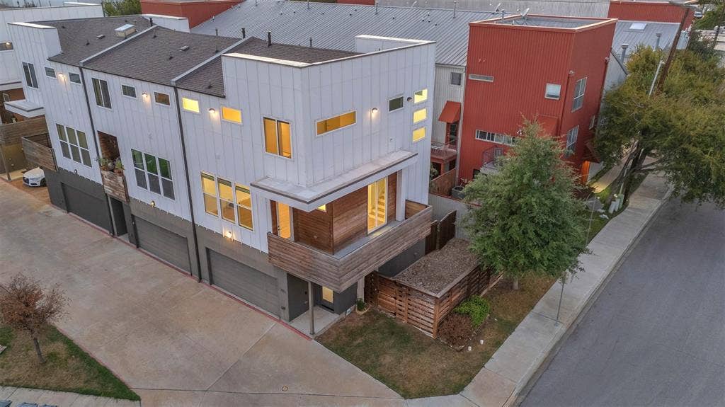 1510 N Washington Avenue, #703, Dallas, TX 75204 Overhead view of the corner unit at dusk with its wood balcony, front entry, 2-car garage and fenced side yard