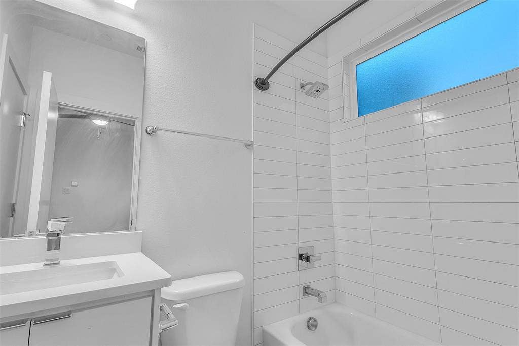1510 N Washington Avenue, #703, Dallas, TX 75204 Secondary bath with a white vanity, tub and shower combo, tall white subway-style wall tile and a frosted window