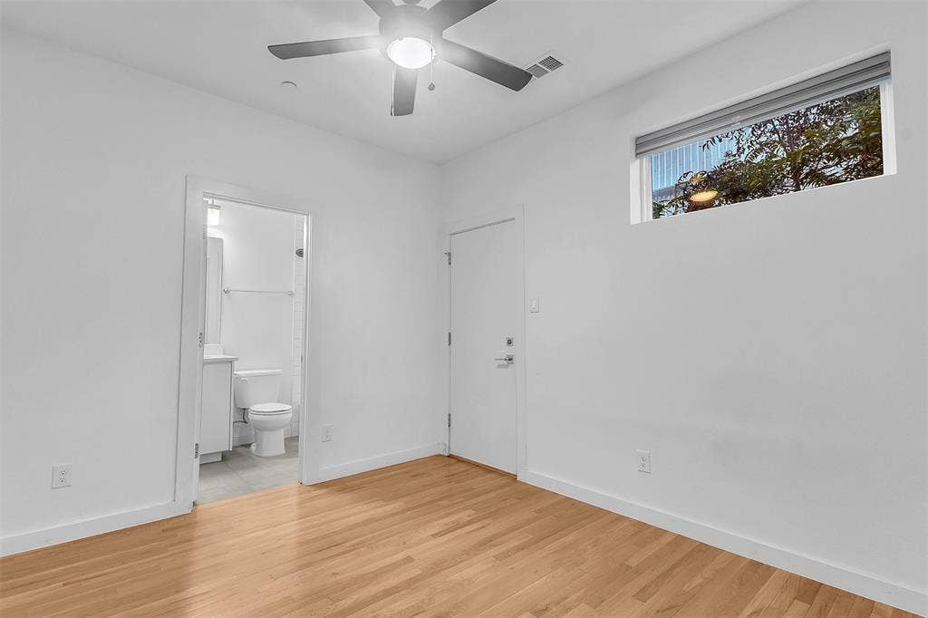 1510 N Washington Avenue, #703, Dallas, TX 75204 Bedroom with an en suite bath, a ceiling fan with light, a transom window with shade and wood-look floors