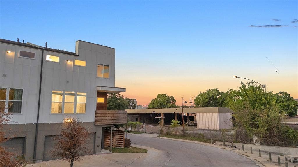 1510 N Washington Avenue, #703, Dallas, TX 75204 Dusk view of this East Dallas condo's corner end unit with a wood balcony, lit windows and the curving side street