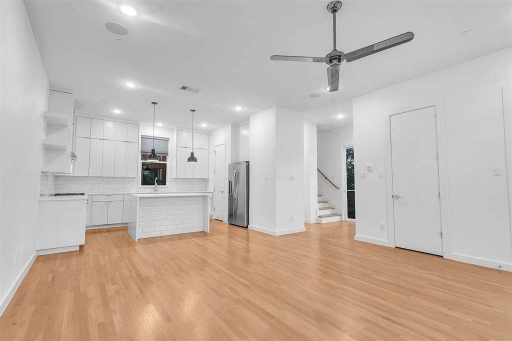 1510 N Washington Avenue, #703, Dallas, TX 75204 Open living and kitchen area in this Dallas condo with wood-look floors, chrome ceiling fan, ceiling speakers and stairs