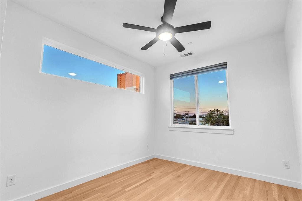 1510 N Washington Avenue, #703, Dallas, TX 75204 Bedroom with wood-look floors, a ceiling fan with light, a long transom window and a second window with shade