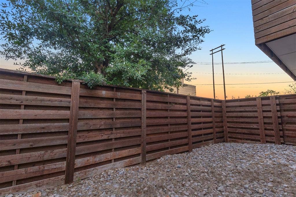 1510 N Washington Avenue, #703, Dallas, TX 75204 Fenced side yard with river rock ground cover, horizontal wood fencing and a mature tree overhead