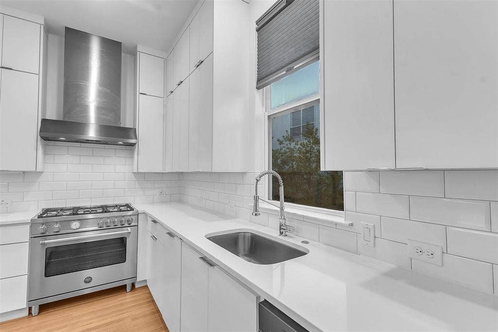 1510 N Washington Avenue, #703, Dallas, TX 75204 Kitchen sink wall with a stainless undermount sink, pull-down faucet, subway tile backsplash and shaded window