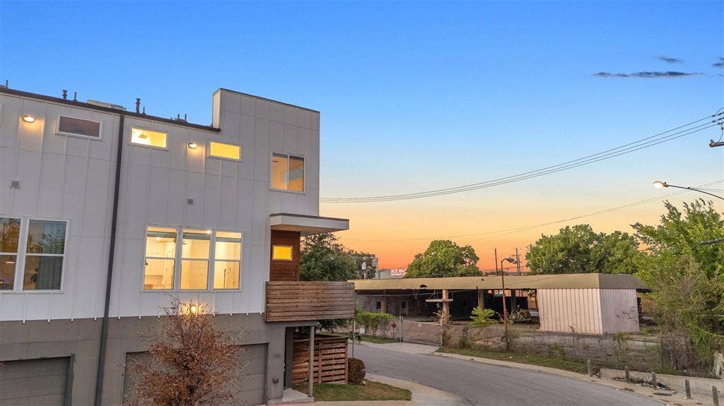 1510 N Washington Avenue, #703, Dallas, TX 75204 Corner end unit at sunset showing board and batten siding, the wood-clad balcony and the fenced side yard