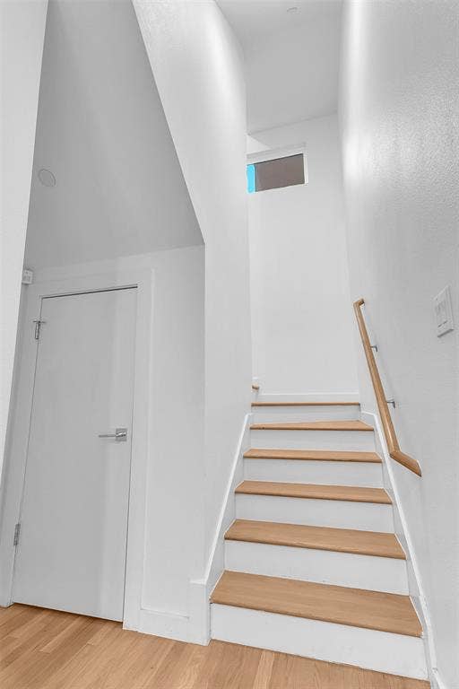 1510 N Washington Avenue, #703, Dallas, TX 75204 Staircase with wood treads, white risers and a wood handrail, with a hall door and a transom window above