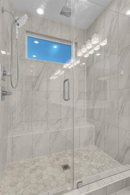 1510 N Washington Avenue, #703, Dallas, TX 75204 Primary walk-in shower with a frameless glass door, built-in bench, rain head, handheld sprayer and hex tile floor