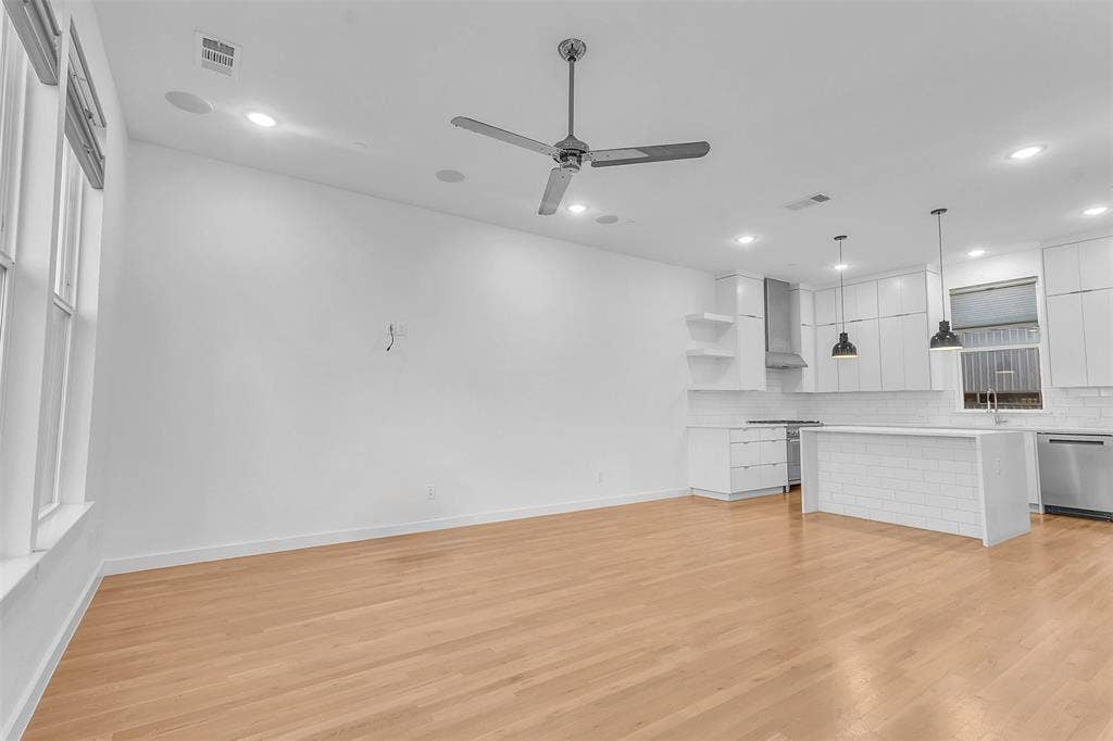 1510 N Washington Avenue, #703, Dallas, TX 75204 Living area looking toward the white kitchen, showing the open layout, recessed lighting and wood-look floors